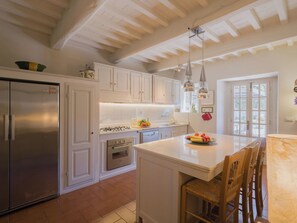 A kitchen with white cabinets, stainless steel appliances, a central island, and pendant lighting.