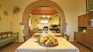 A dining area with a brick archway, a table set with plates, glasses, and a fruit centerpiece. - Lovely apartment for 4 people with WIFI, A/C, TV and panoramic view (Cortona)