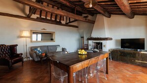 A spacious living area with a wooden ceiling, a large mirror, a sofa, a coffee table with a fruit bowl, and a television. - Beautiful apartment for 4 people with A/C, WIFI, TV, terrace, pets allowed and panoramic view (Cortona)