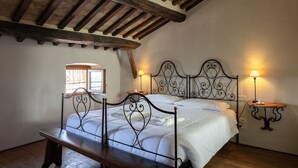 A bedroom with a wooden ceiling, a metal bed frame, a wooden bench, and two bedside lamps. - Beautiful apartment for 4 people with A/C, WIFI, TV, terrace, pets allowed and panoramic view (Cortona)