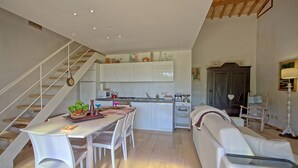 A modern kitchen with white cabinets, a dining area with white chairs, and a staircase. - Capannino - Holiday House Rental near Siena, Tuscany (Ponte A Bozzone)