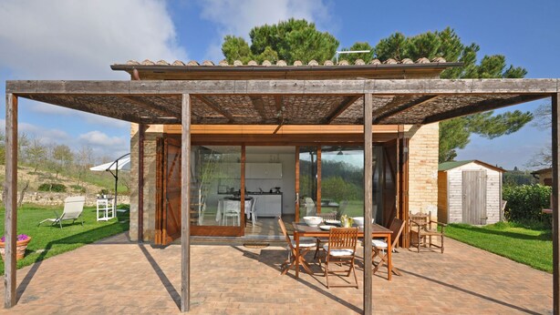 A modern outdoor dining area with a pergola, a brick patio, and a view of the surrounding landscape. - Capannino - Holiday House Rental near Siena, Tuscany (Ponte A Bozzone)