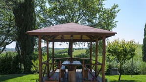 A wooden gazebo with a table and benches, surrounded by stone pathways and lush greenery. - Wonderful  villa for 4 guests with A/C, WIFI, private pool, TV and panoramic view, close to Cort... (La Villa-farneta)