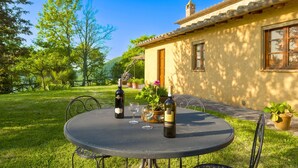 An outdoor dining area with a round table, two wine bottles, and a potted plant. - Beautiful private villa for 9 guests with WIFI, private pool, TV, veranda and pets allowed (Cortona)