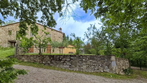 A stone building with a gravel driveway and a stone wall.