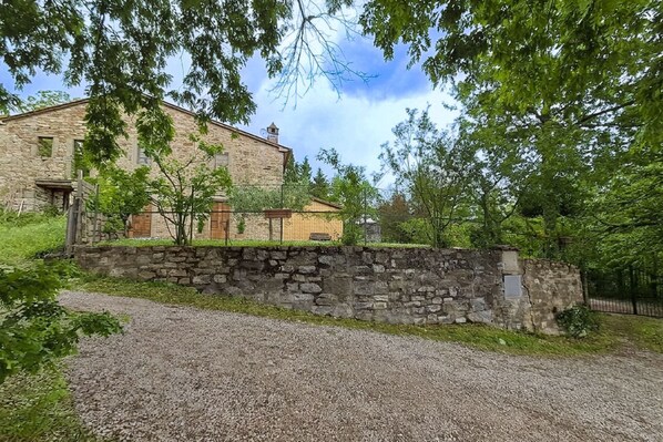 A stone building with a gravel driveway and a stone wall.