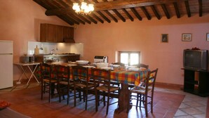A cozy kitchen with wooden beams, a dining table set for six, and a television in the corner. - Lovely apartment for 10 guests with pool, WIFI, TV and pets allowed (Camucia-monsigliolo)