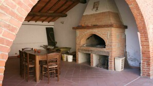 An outdoor brick oven with a table and chairs nearby. - Lovely apartment for 10 guests with pool, WIFI, TV and pets allowed (Camucia-monsigliolo)