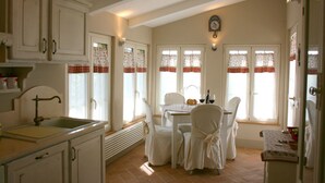 Una cocina con armarios blancos, un lavamanos y un comedor con mesa y sillas.
