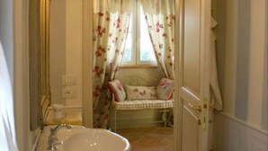 Un baño con lavamanos, espejo y ventana con cortinas florales.