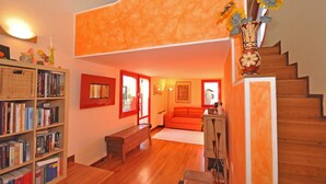 A spacious living room with a wooden staircase, a bookshelf filled with books, a sofa, and a bench. - Wonderful private villa with A/C, private pool, WIFI, TV and panoramic view, close to Cortona (Montecchio)