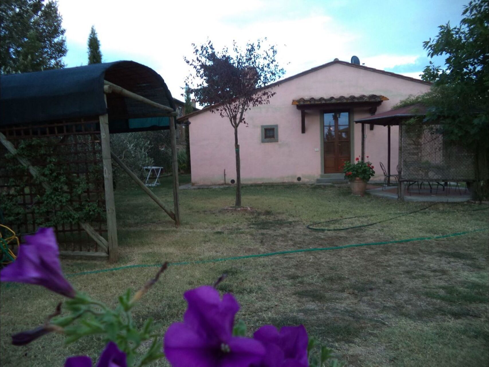 Ein eingeschossiges Haus mit kleinem Garten, überdachter Veranda und Schaukel.