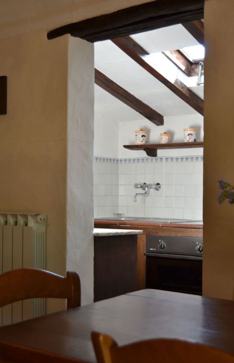 Eine Küche mit einem Holztisch und -stühlen, einer gefliesten Spritzschutzwand und einem Fenster über der Spüle.