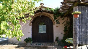 A rustic building with a dark wooden door, a small window, and a brick entrance. There is a potted plant and a table with a yellow tablecloth outside. - Cosy apartment for 6 guests with WIFI, pool, A/C and TV (Camucia-monsigliolo)