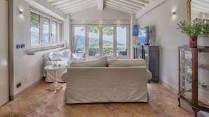 A spacious room with a high ceiling, a sofa, a small table, and a cabinet with glass doors. - Stunning private villa with A/C, WIFI, private pool, TV, patio and panoramic view, close to Cort... (Poggioni)