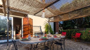 An outdoor dining area with a round table set for six, surrounded by black metal chairs.