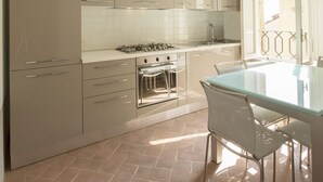 Una cocina moderna con armarios blancos, una mesa de comedor de vidrio y luces rojas colgantes.