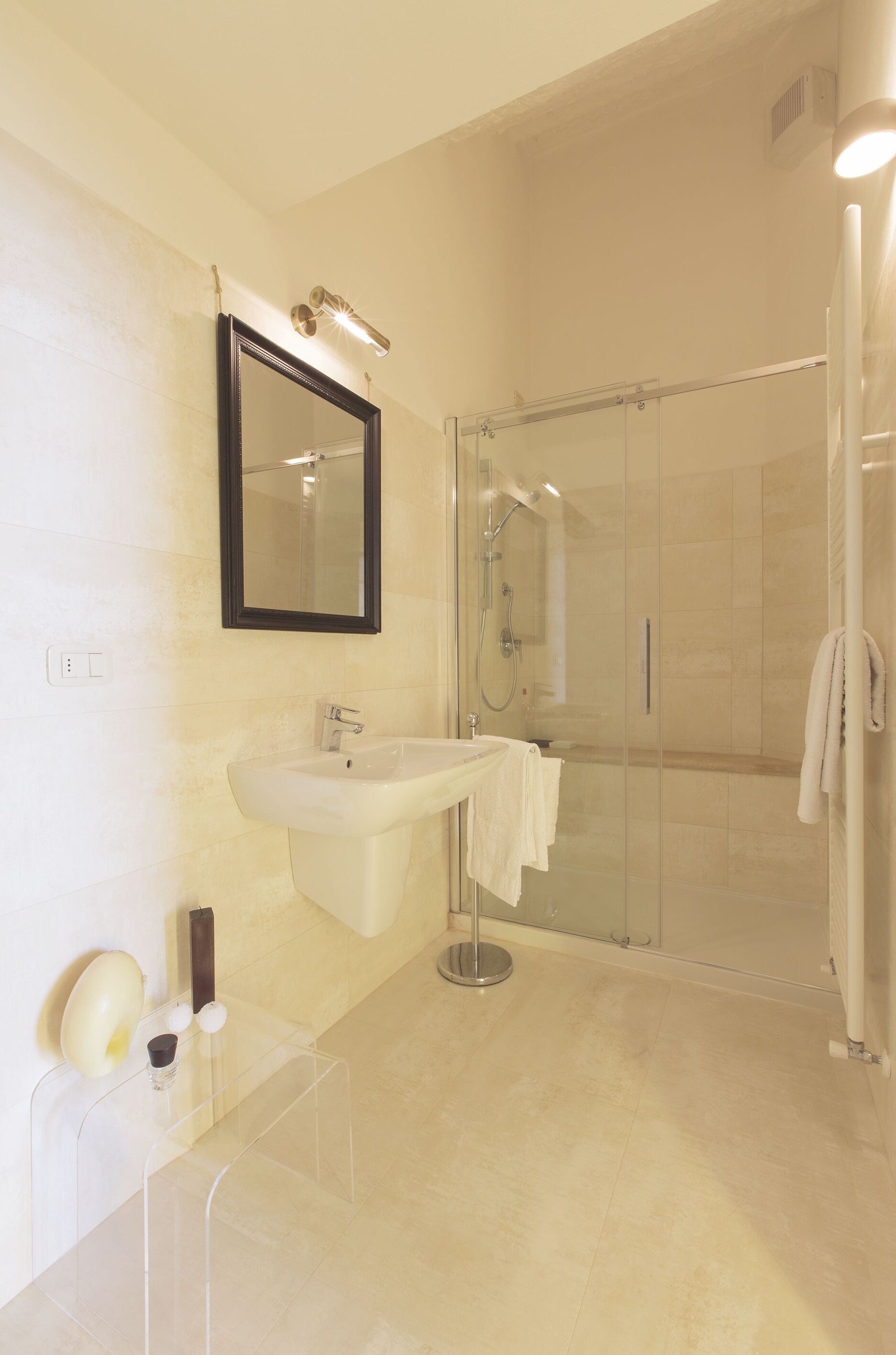 A modern bathroom with a glass shower enclosure, a white sink, and a large mirror.