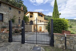 A stone house with a gated entrance, a stone wall, and a tall tree in the background. - Private Villa with hot tub, WIFI, sauna, pool, A/C, TV, terrace, panoramic view, close to Cortona (Torreone)
