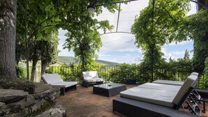An outdoor patio with wicker furniture, stone walls, and a view of a hilly landscape. - Private Villa with hot tub, A/C, sauna, WIFI, pool, TV, terrace, panoramic view, close to Cortona (Torreone)