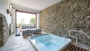 A stone-walled room with a pool, two striped sofas, and a radiator. - Private Villa with hot tub, A/C, sauna, WIFI, pool, TV, terrace, panoramic view, close to Cortona (Torreone)