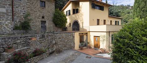 A stone building with a modern extension, a gravel driveway, and a well-maintained garden.