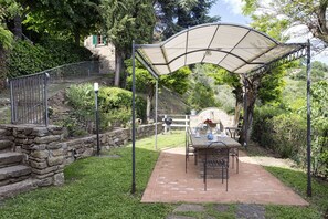 A patio with a table and chairs, a stone wall, and a pergola. - Private Villa with hot tub, WIFI, sauna, pool, A/C, TV, terrace, panoramic view, close to Cortona (Torreone)