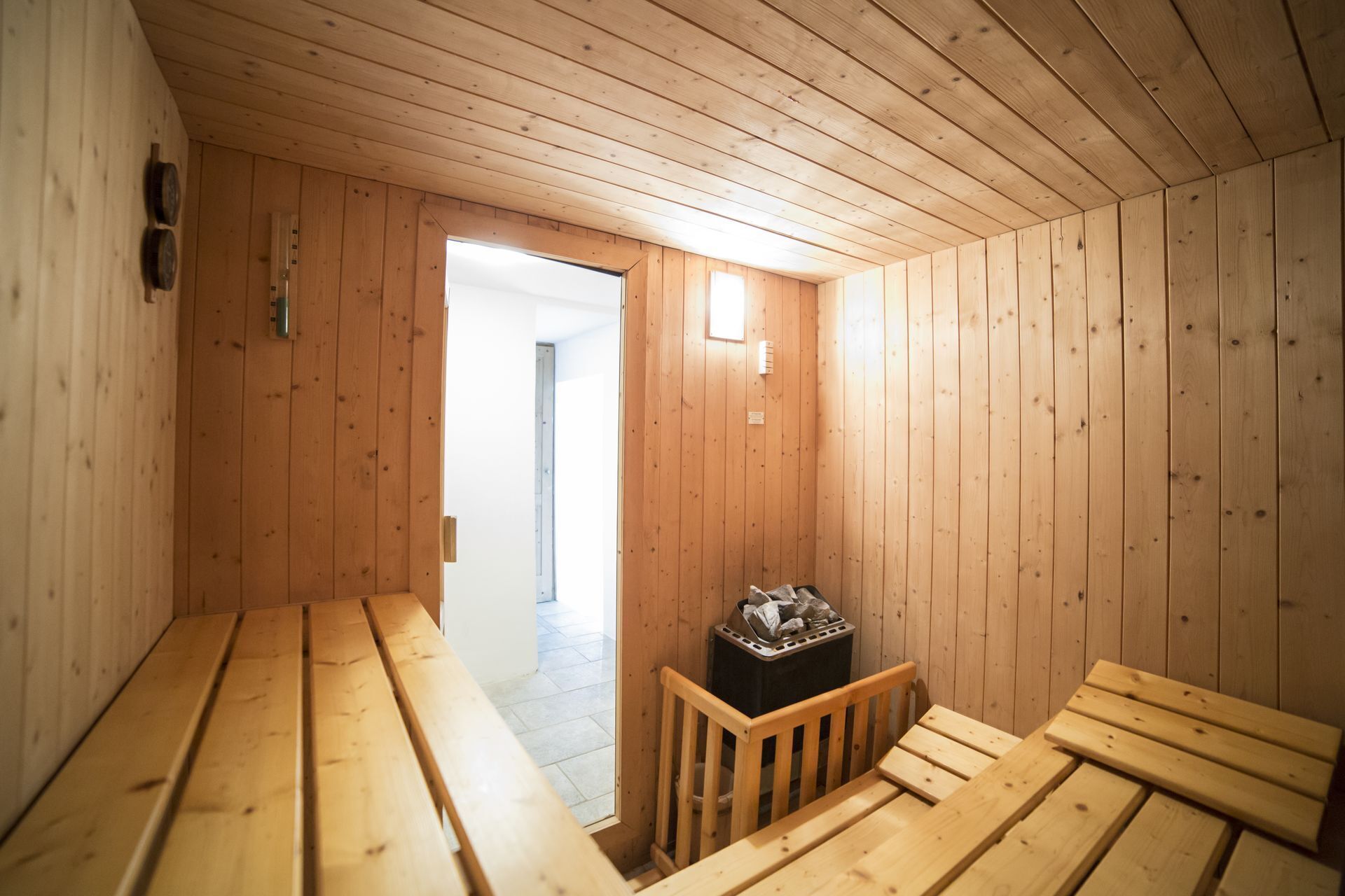 Uma sala de sauna de madeira com bancos e um cesto de lixo.