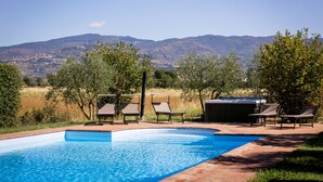 A swimming pool with lounge chairs and a hot tub, surrounded by trees and a view of mountains. - Private Villa with hot tub, A/C, private pool, WIFI, TV, patio, panoramic view, close to Cortona (Terontola)