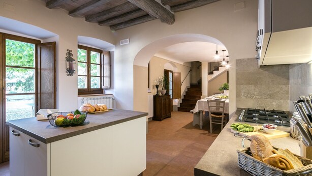 A kitchen with a central island, a dining area with a table and chairs, and a staircase leading to another level. - Private Villa with hot tub, A/C, private pool, WIFI, TV, patio, panoramic view, close to Cortona (Terontola)