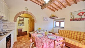 Un coin repas accueillant avec une table dressée pour quatre personnes, une cuisine équipée d’une cuisinière et d’un évier, et un salon avec un canapé.