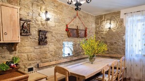Une cuisine rustique aux murs en pierre, avec des meubles en bois et un vase rempli de fleurs jaunes.