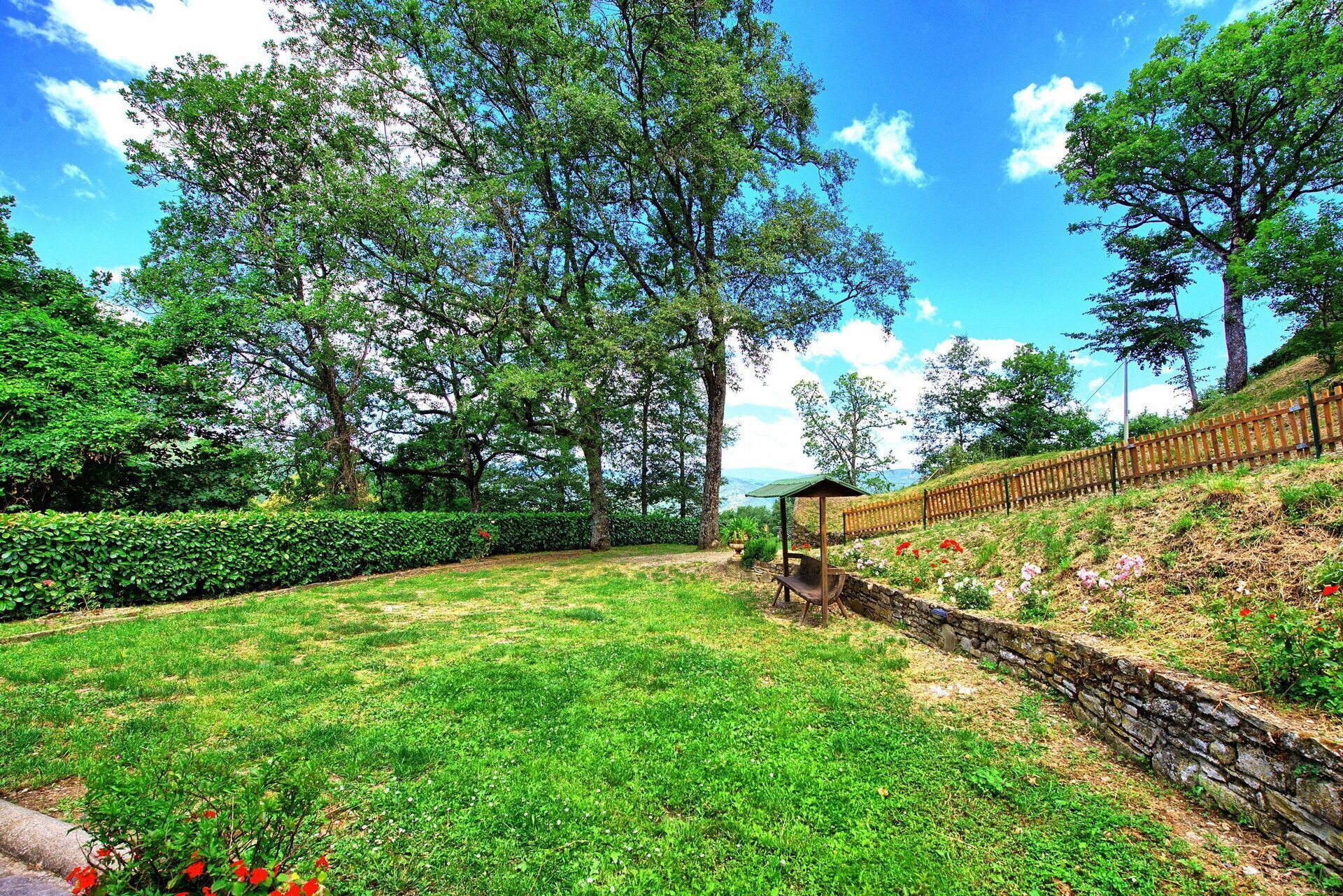 Un espacio cubierto de césped con un muro de piedra y una valla de madera.