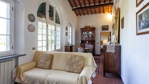 A cozy room with a sofa, a wooden cabinet, and a dining table. - Casa Vittoria 1 - Apartment with swimming pool (Cortona)