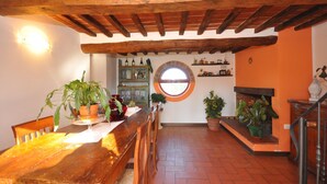 A rustic interior with a wooden dining table, chairs, a fireplace, and a window with a view. - Casa Laura - House with private pool (Montecchio)