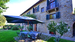 A stone building with a patio area featuring a table and chairs under a large umbrella.