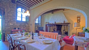 A dining area with a stone wall, a fireplace, and a table set for a meal.