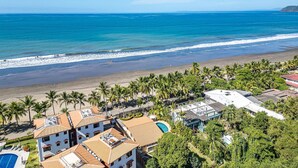 A coastal hotel with multiple buildings, a swimming pool, and a beach view.