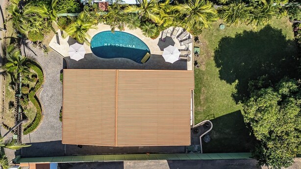 An aerial view of a resort with a swimming pool labeled "MANDOLINA," a covered seating area, and surrounding greenery. - Casa Mandolina on the beach in Jaco (Jaco)