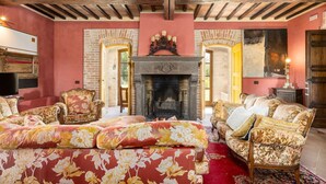 A room with a fireplace, floral upholstery, and a red carpet.