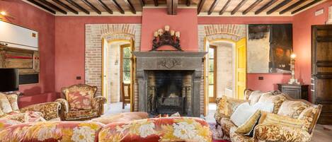 A room with a fireplace, floral upholstery, and a red carpet.