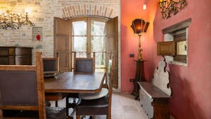 A rustic dining area with a wooden table and chairs, stone walls, and a red accent wall.