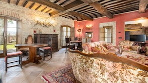 A rustic interior with exposed wooden beams, a stone fireplace, and traditional furnishings.