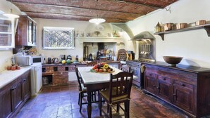 Una cocina rústica con techo de ladrillo, armarios de madera y una mesa de comedor dispuesta con verduras.