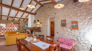 Un comedor rústico con una mesa de madera, sillas y una pared de piedra.