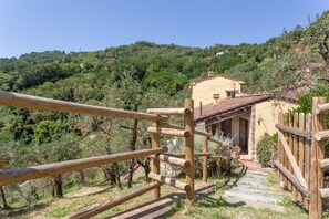 A rustic wooden fence leading to a stone staircase and a yellow building with a tiled roof, surrounded by lush greenery and hills. - Country House / Farm House in Mastiano with 4 bedrooms sleeps 8 (San Concordio Di Moriano)