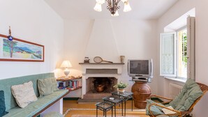 Una sala de estar acogedora con sofá, sillón, chimenea, televisión y un cuadro en la pared.
