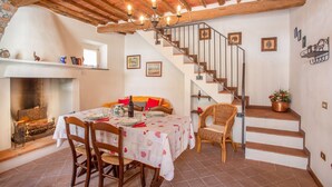Un comedor con una mesa dispuesta para cuatro, una chimenea y una escalera que sube.