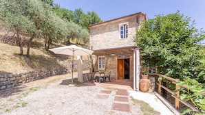 Una casa in pietra con una porta di legno, un piccolo patio con tavolo e sedie e un muro in pietra.