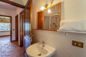 Ein Badezimmer mit einem weißen Waschbecken, einem Spiegel und einem Handtuchhalter.
